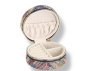 Coffre à bijoux rond multicolore avec fermeture zippée dorée et intérieur crème compartimenté pour bagues, colliers et boucles d’oreilles. Écrin original, chic et pratique pour protéger et ranger vos bijoux avec élégance.