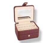 Coffre à bijoux Prestige bordeaux aspect cuir grainé avec compartiments pour bagues, boucles d’oreilles, colliers et bracelets. Coffret élégant avec intérieur crème, miroir intégré et fermeture à pression pour protéger et organiser vos bijoux avec raffinement.